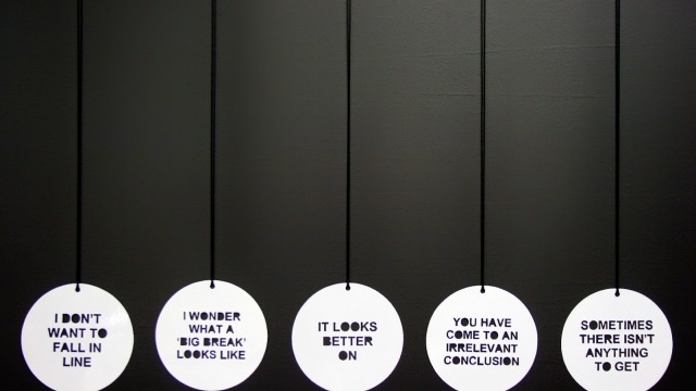 Zoe Brand exhibtis in 'Intimately Connected' Zoe Brand, 'A failure to communicate, more or less' 3 of 14 signs/pendants from the series. Powdercoated alumunium, 140 x 0.5mm