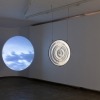 Anna May Kirk, Year Without a Sun, 2023. Volcanic sand from Mount Tambora, glass, mild steel frame, video, projector, circular projection screen (65 × 65 × 1 cm), 14 minutes 35 seconds, 2023. Photo credit Jessica Maurer. 